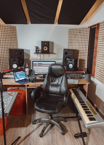 Vertical shot of an interior of a sound engineer, musician, composer's workplace for broadcasting. Music rehearsal space with drum kit and musical equipment.