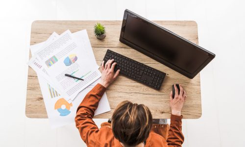 top-view-of-man-working-on-computer-at-table-with-2022-12-16-18-36-51-utc